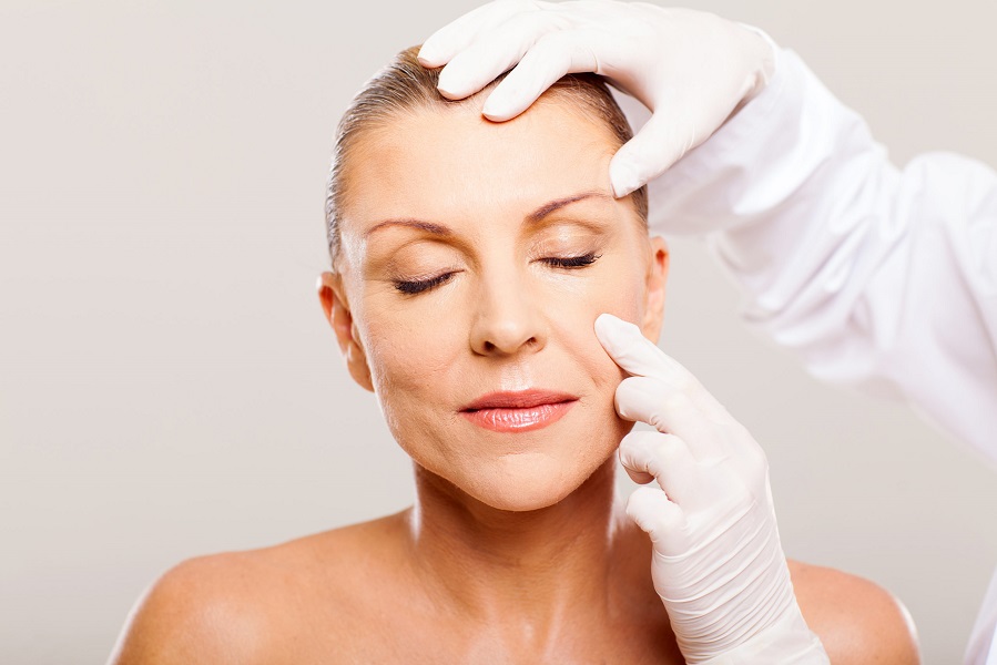 doctor examining mid age woman skin before cosmetic surgery | Kay Dermatology in Burbank, CA