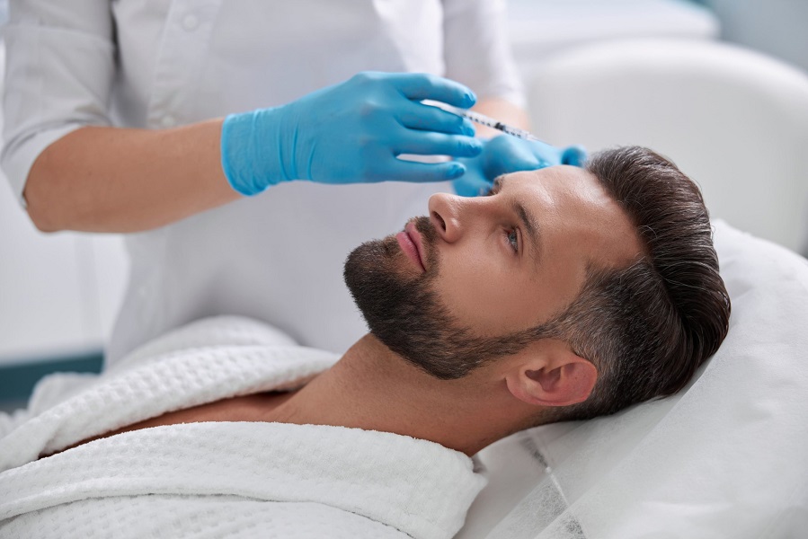 Beautician doctor hands doing beauty procedure to male face with syringe. Young man's forehead contouring with filler injection. Marionette lines treatment - Juvederm filler treatments | Kay Dermatology in Burbank, CA